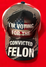 Load image into Gallery viewer, SALE !! I’m voting for the convicted felon - Hat -camo, American flag faded, back - red &amp; white stripes. Available for purchase @ TrumpGirl.com